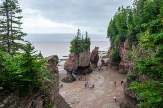 Imagine olhar para o mar e vê-lo desaparecer. Não como uma ilusão de ótica, nem como um truque de câmera, mas como um fenômeno real, previsível e tão extremo que permite algo quase inimaginável: caminhar até uma ilha atravessando o fundo do oceano.